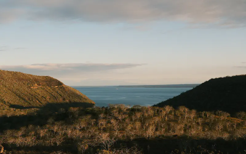 View of a Galapagos bay framed by dry volcanic hills at golden hour